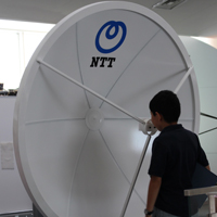 パラボラアンテナとその前に立っている少年の写真