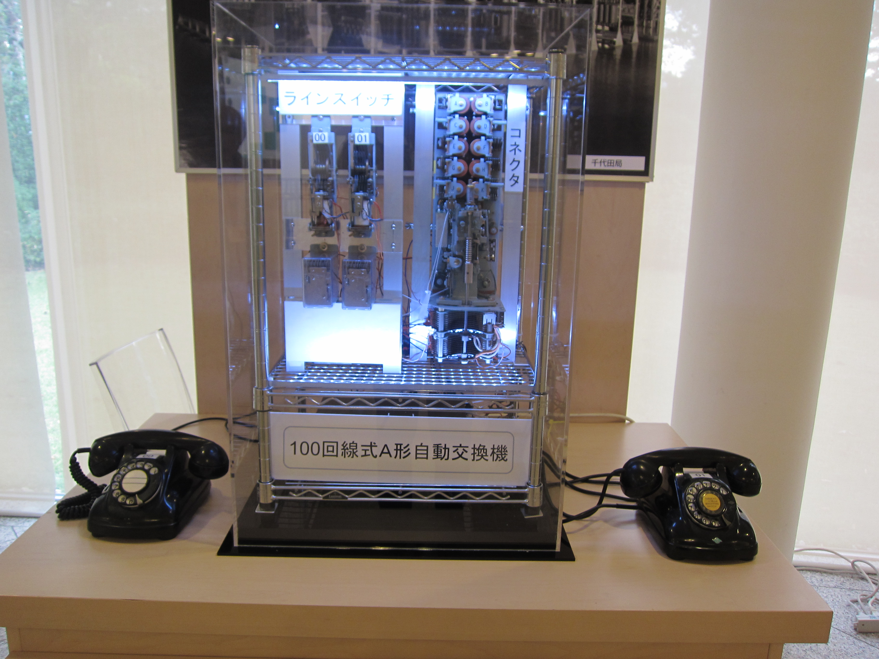 LEDライトを設置し、アクリルケースに入ったA型自動交換機の写真