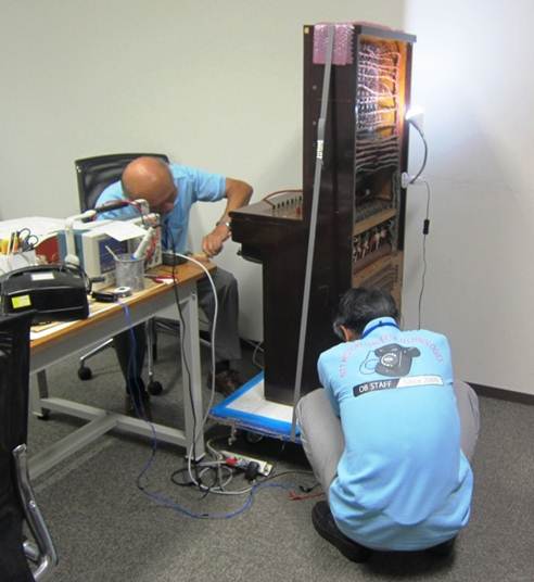 磁石式手動交換機の復元作業をする寺脇さんと千葉さんの写真