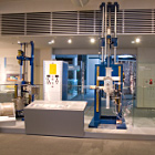 右から大型光ファイバ母材、VAD法光ファイバ母材製造装置、透明化装置の写真